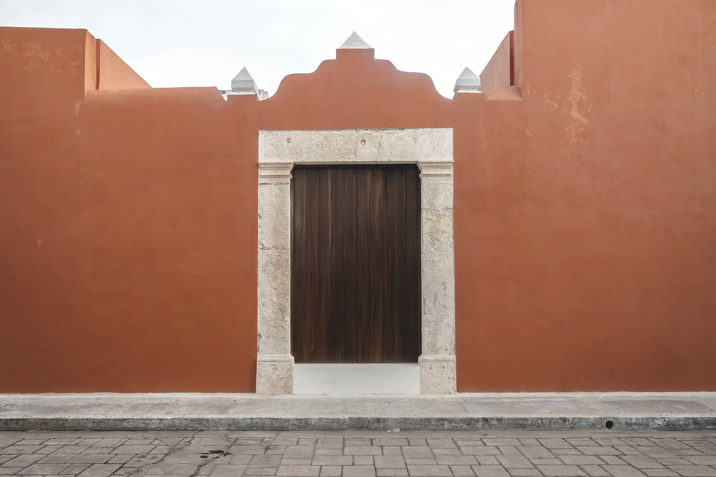 Fachada terracota de Casa Ex Templo con remate mixtilíneo y portón de madera, en Campeche