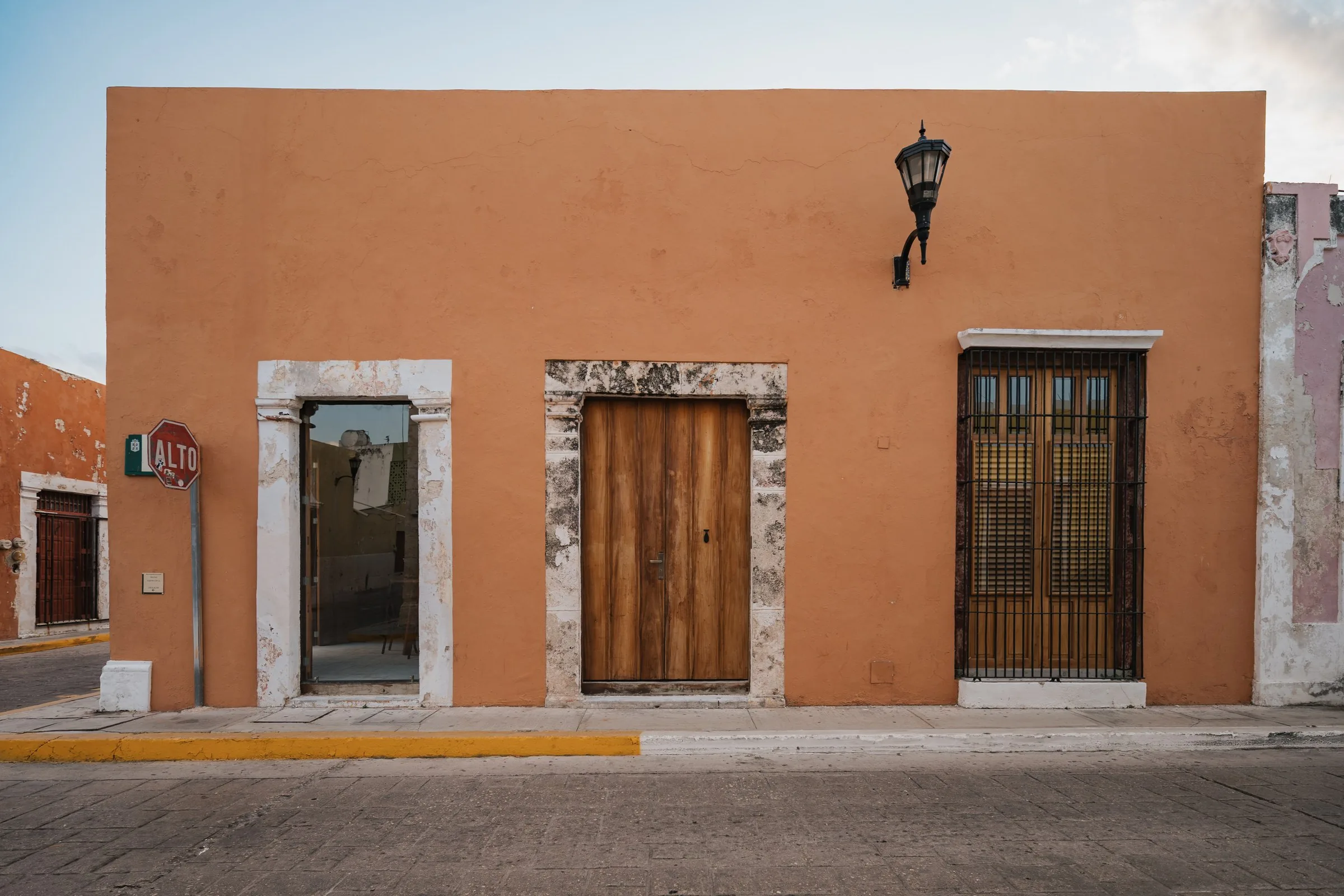 Fachada terracota de Casa Zotz con puertas de madera y un farol, en la ciudad amurallada de Campeche