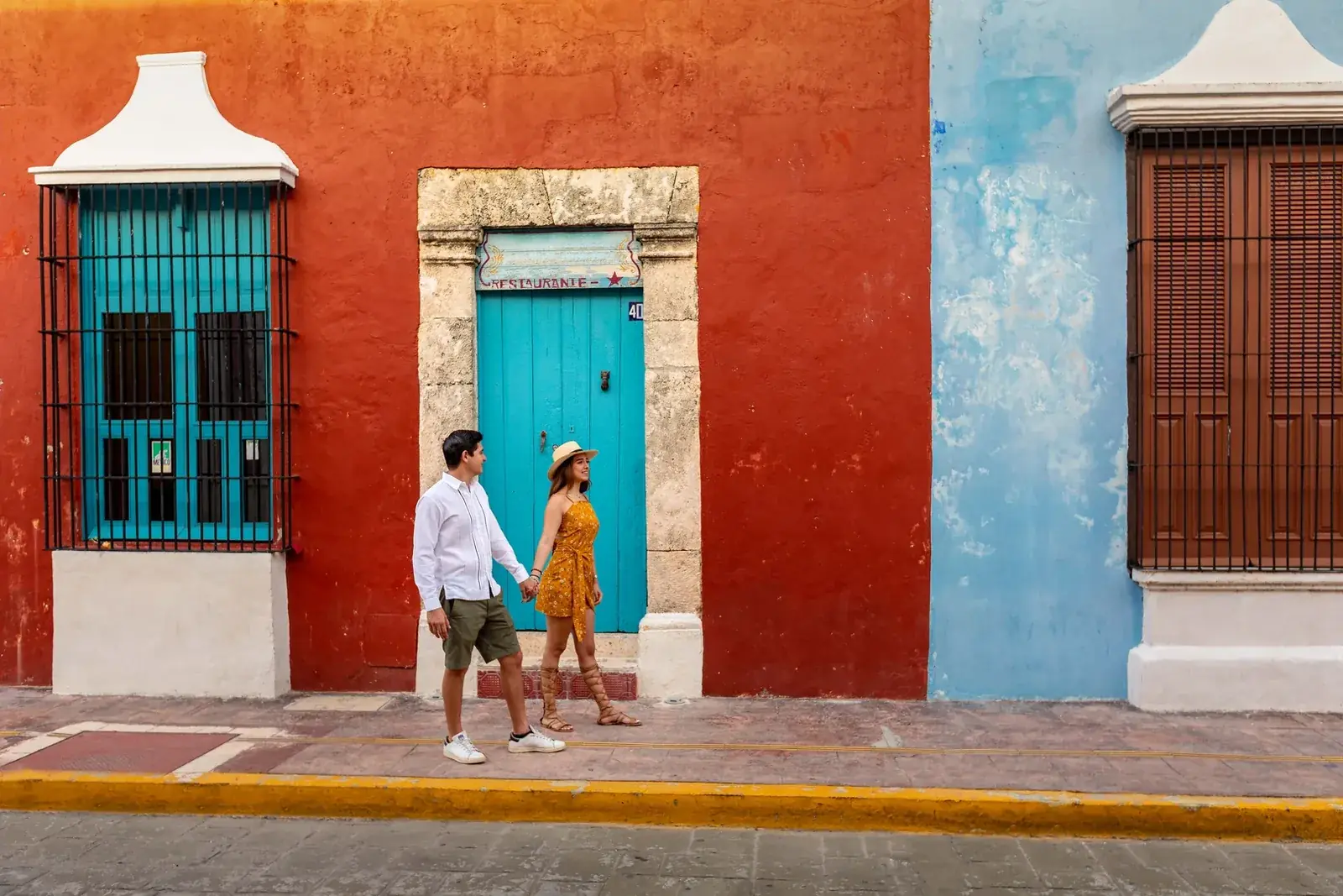 Pareja caminando frente a las fachadas de colores del centro histórico de Campeche. Casonas MX