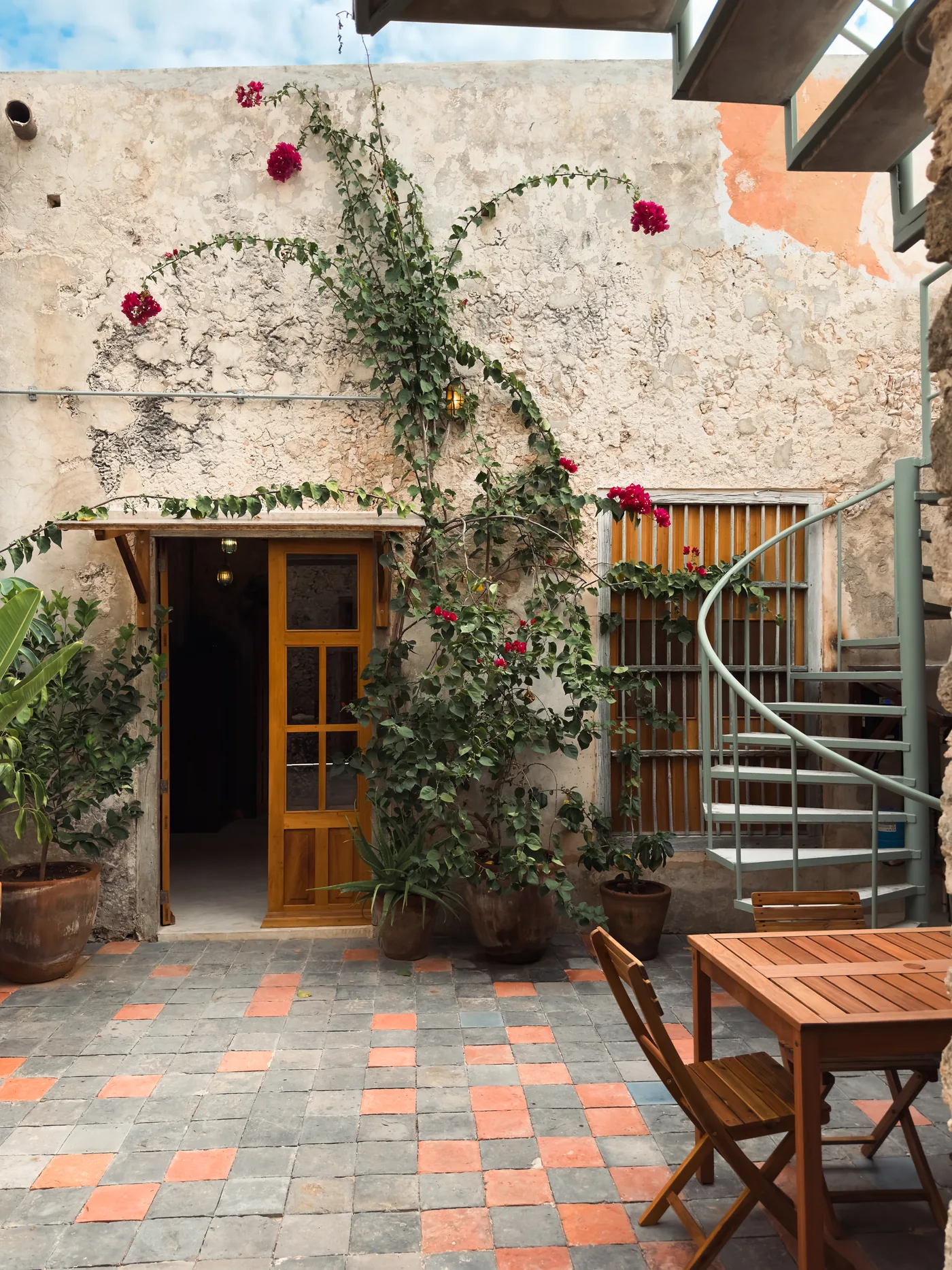 Patio de una casona restaurada en Campeche con buganvilia, muros de piedra y piso de pasta
